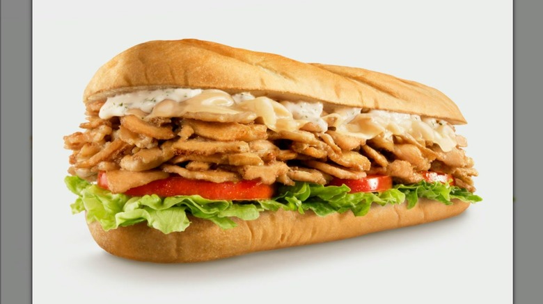 Sub sandwich with chicken, melted cheese, ranch dressing, lettuce, and tomatoes