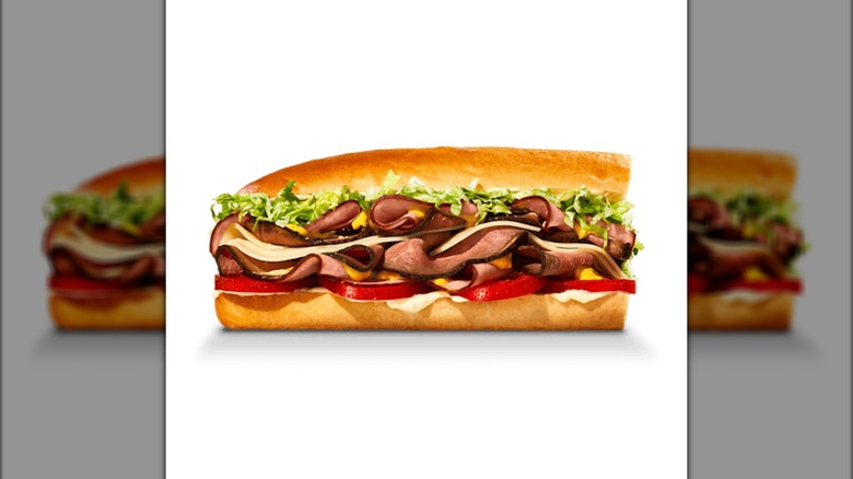 Sub sandwich with sliced roast beef, ham, cheese, tomatoes, and lettuce