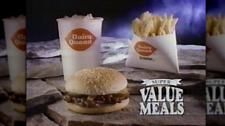 A hamburger, a package of french fries, and a Dairy Queen branded drink with text that reads "Super Value Meals" to the front right