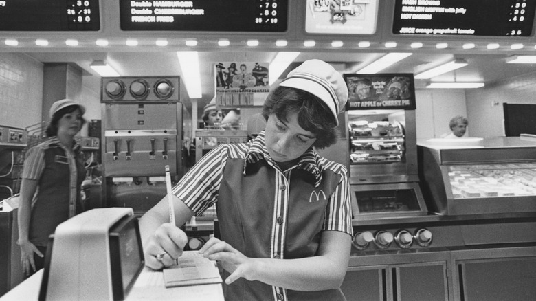 An employee writing down an order at the counter of a McDonald's in the 1970s
