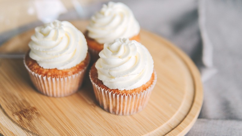 cup cakes with buttercream frosting on a wooden board
