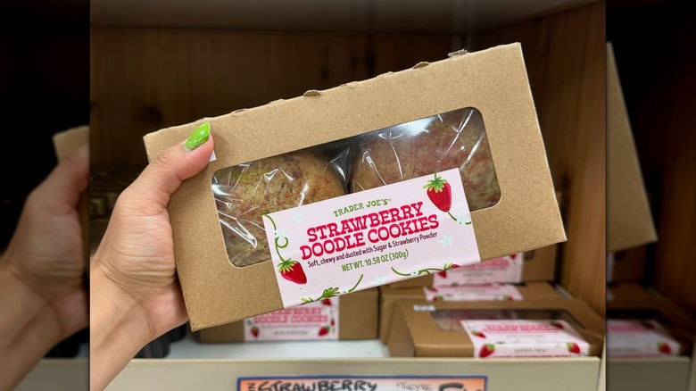 A hand holding a box of Trader Joe's Strawberry Doodle Cookies