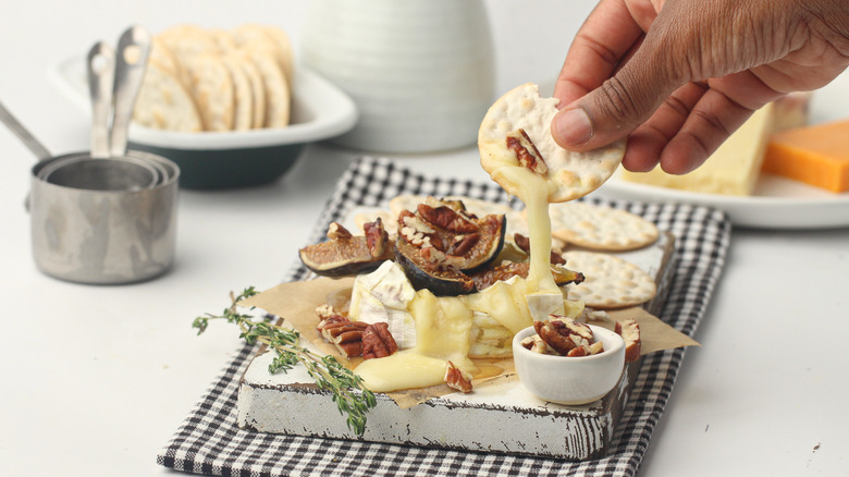 hand scooping Brie with cracker