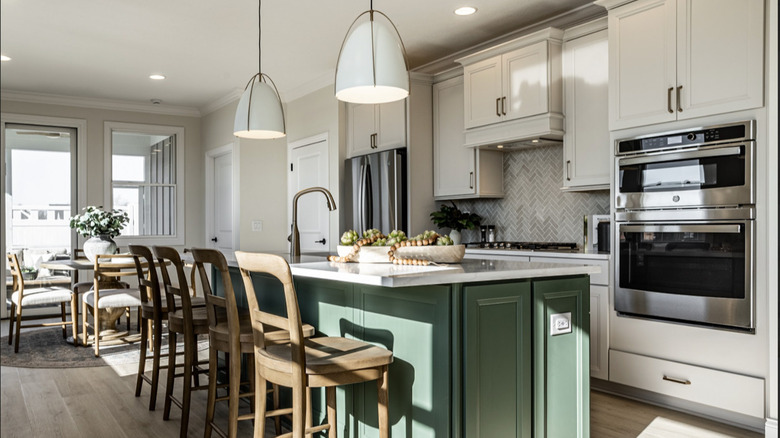 View into a kitchen with an island featuring pendant lighting, a sink in the island, and other visual elements