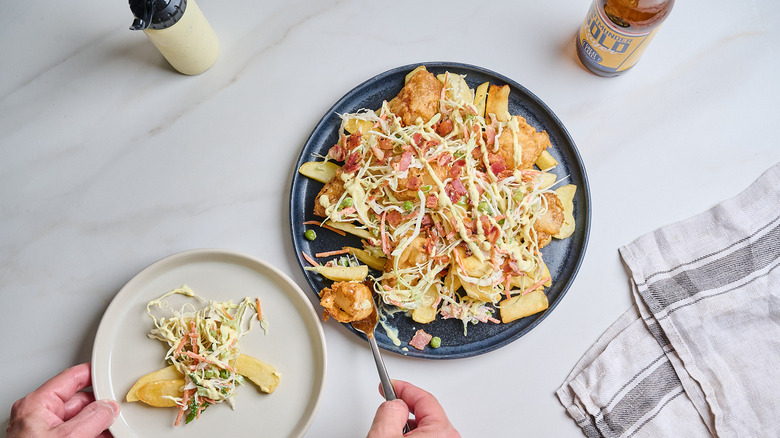 platter of loaded fries with fish and coleslaw on a table
