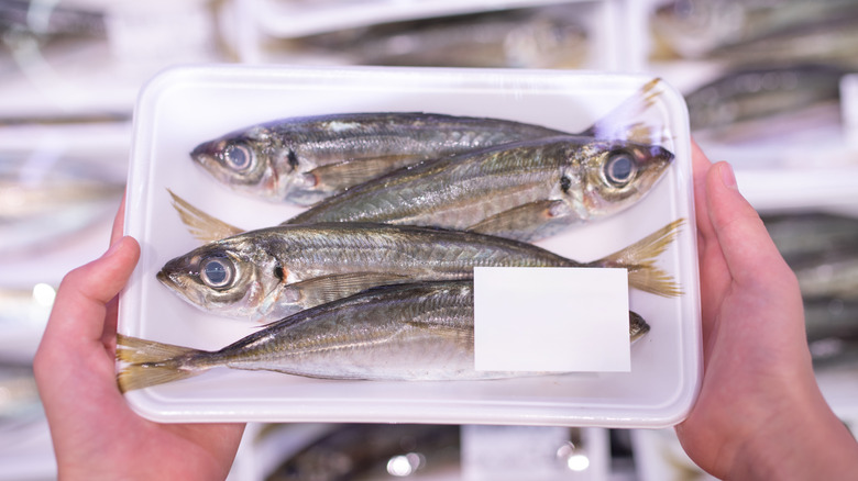 A person holds whole, packaged fish