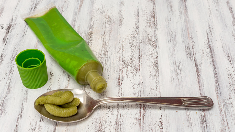 Spoonful of wasabi paste next to green wasabi bottle