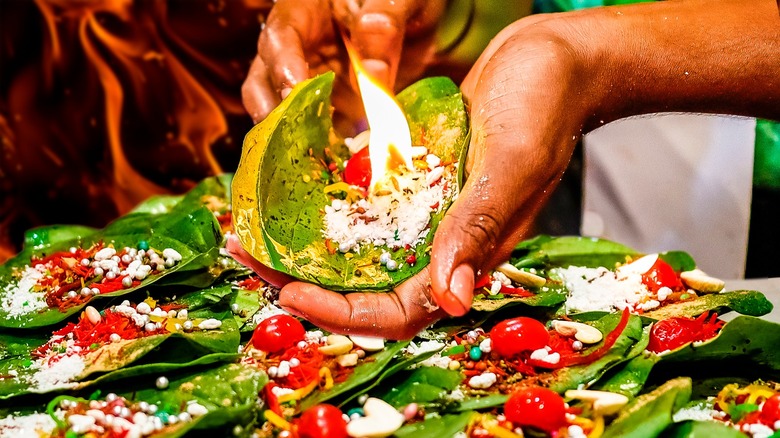 Hands holding paan on fire