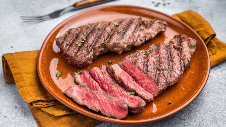 A grilled flat iron steak sits on a ceramic plate.