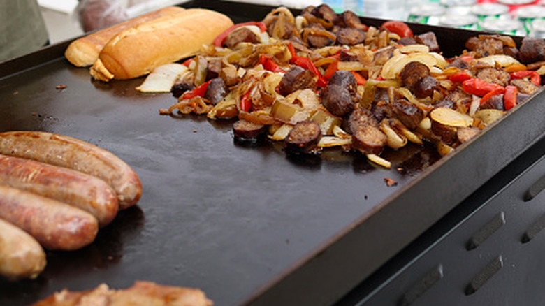 Flat-top grill with sausage and other food cooking on it