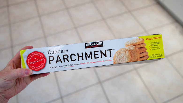 A hand holding a package of culinary parchment paper