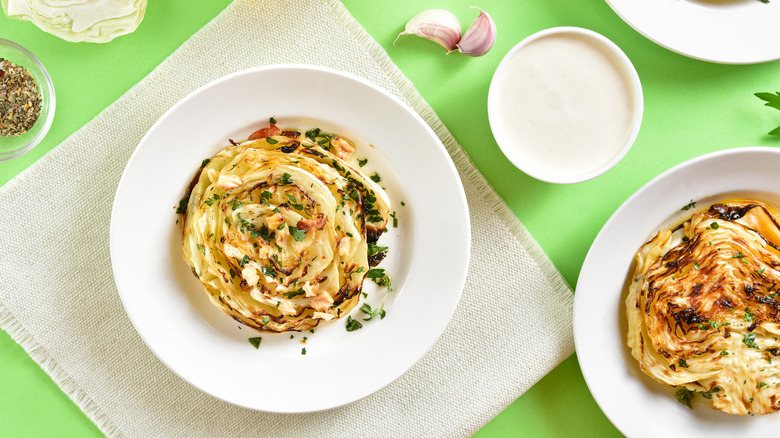 Cabbage steaks on plates with white sauce