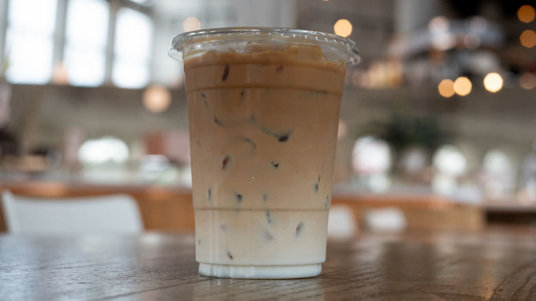 An iced vanilla latte in a plastic cup on a table in a coffee shop