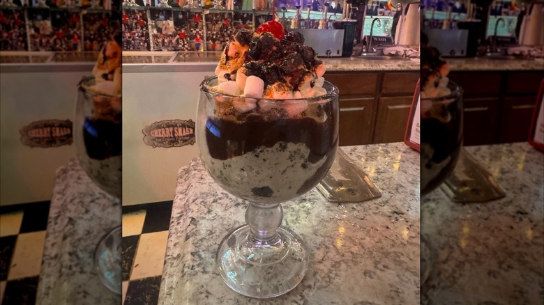 Ice cream sundae in glass cup with soda fountain behind it