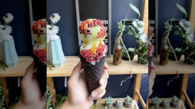Ice cream cone with sprinkles with drizzle against plants in the background