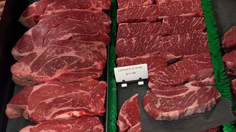 Raw cuts of beef in butcher display case.