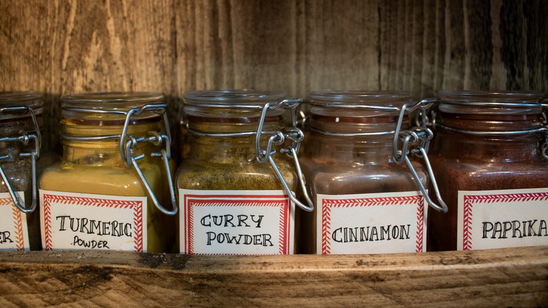 Labeled spice jars in a wooden spice rack