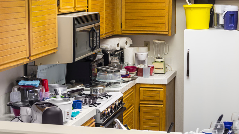 Messy kitchen with oak cabinets and cluttered countertops