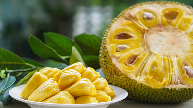 jackfruit cut in half and displayed next to picked jackfruit on a white plate