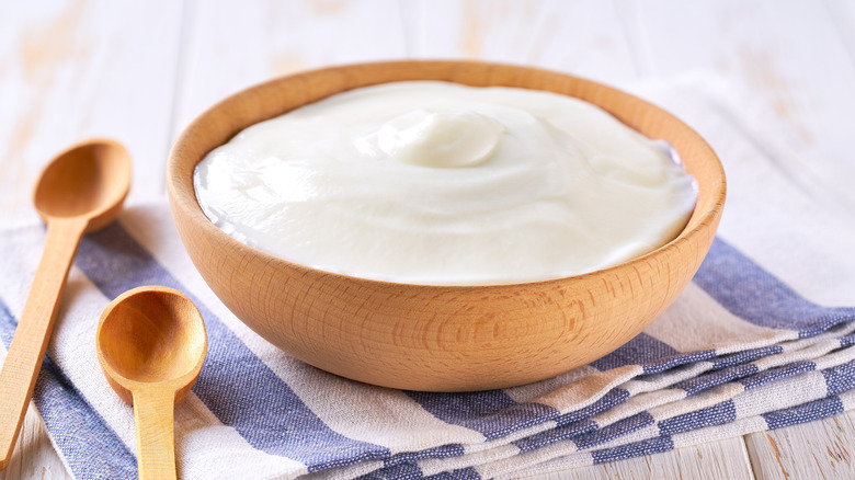 a wooden bowl filled with yogurt and spoons next to it