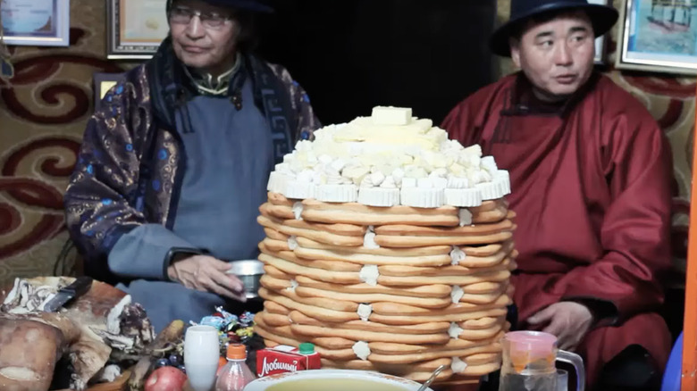 Two Mongolian men sitting in front of an ul boov cake