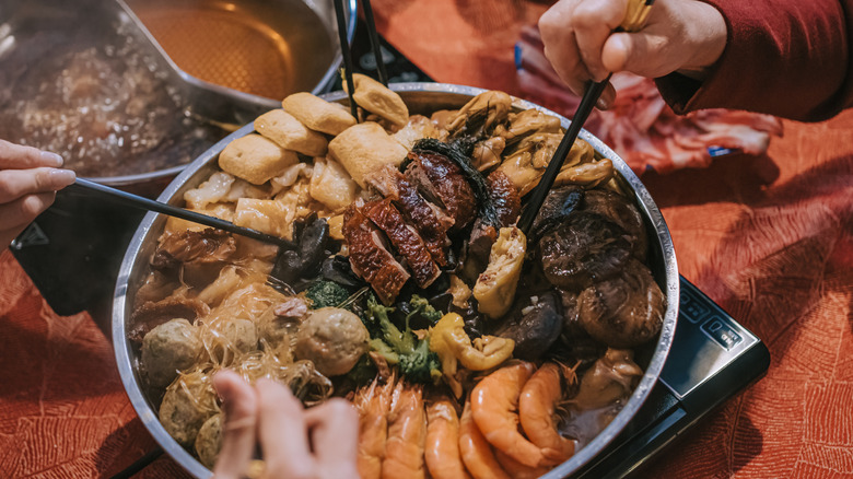 Several people enjoying hot pot with chopsticks