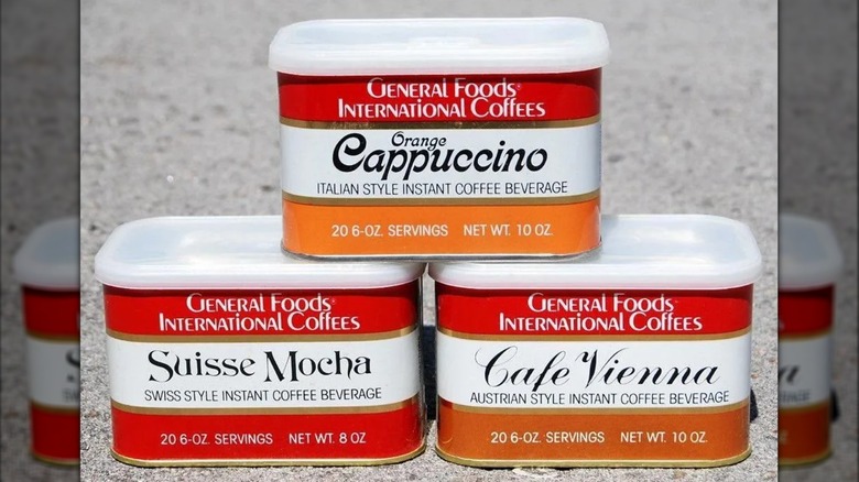 Three cans of General Foods International Coffees in Orange Cappuccino, Suisse Mocha, and Cafe Vienna flavors, sit on a counter.