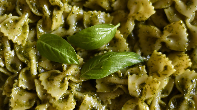 Bowtie pasta tossed in pesto sauce with fresh basil leaves on top.