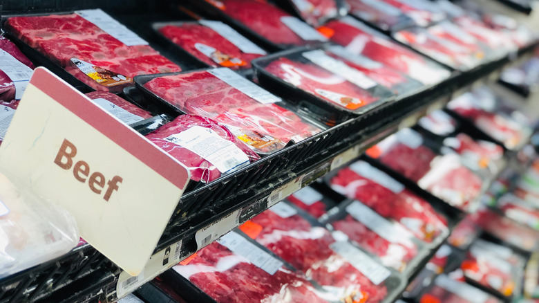 A selection of raw beef products on display in the aisle of a supermarket