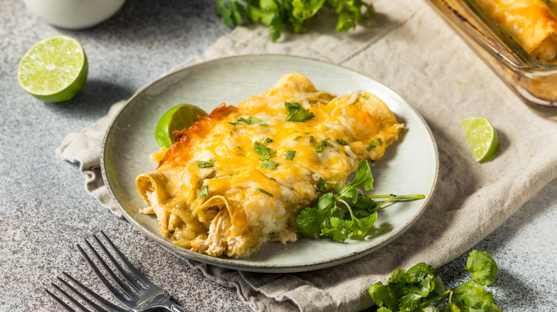 Plate with two enchiladas, cilantro, and lime wedge