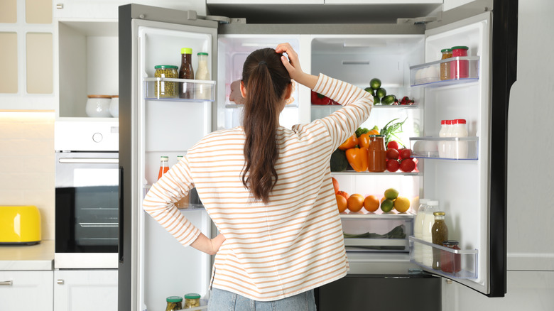 Person opening and looking into refrigerator