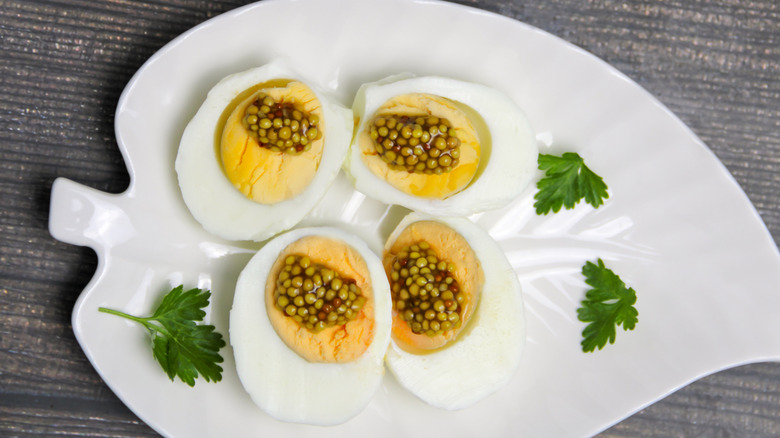 Halved hard-boiled eggs with mustard on dish