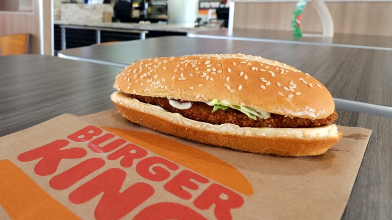 Burger King original chicken sandwich sitting on Burger King logo brown napkin on gray table
