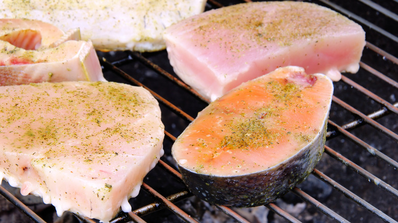 Selection of seasoned fish steaks on grill