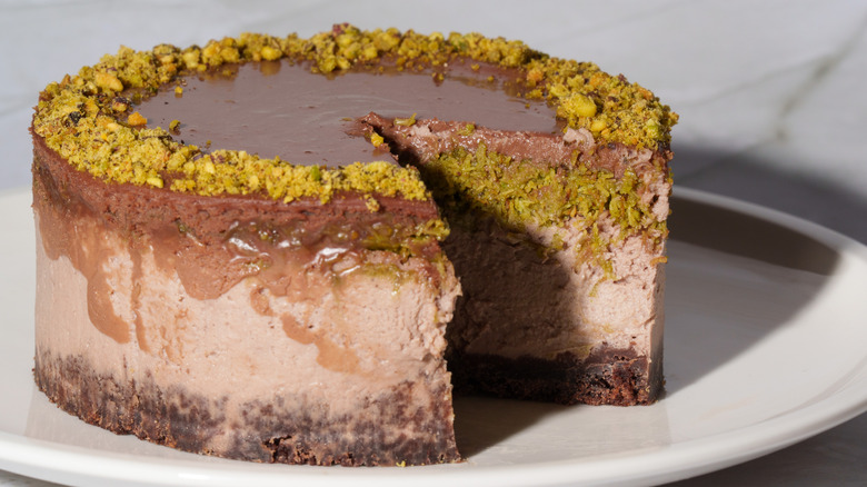 Chocolate cheesecake on stand with piece missing