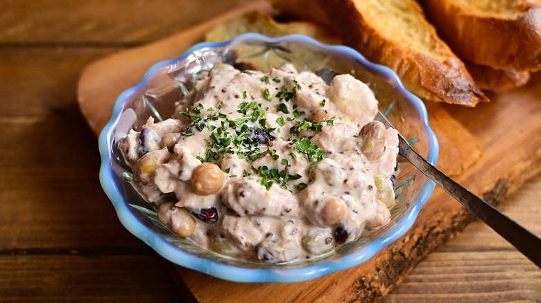 dip with duna, beans, may, herbs, in a class dish with pieces of toast besides