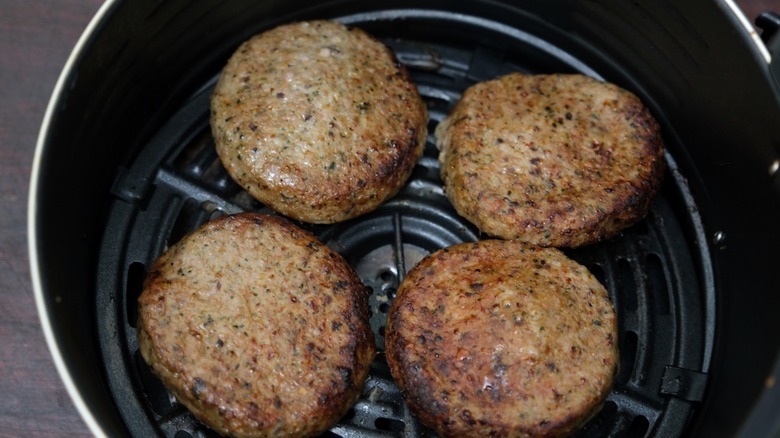 Turkey burger patties cooking in an air fryer basket