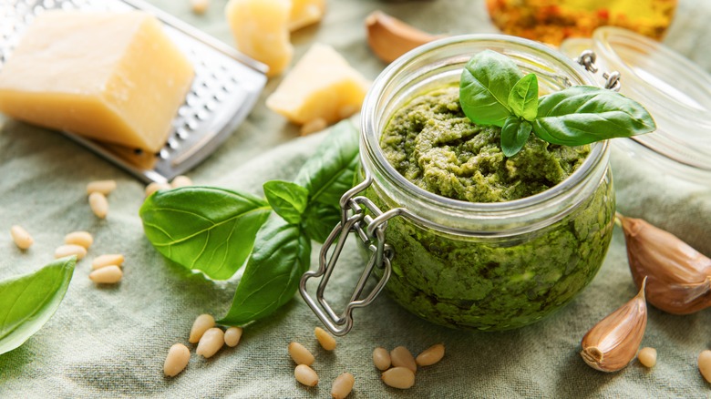 A jar of pesto and its ingredients
