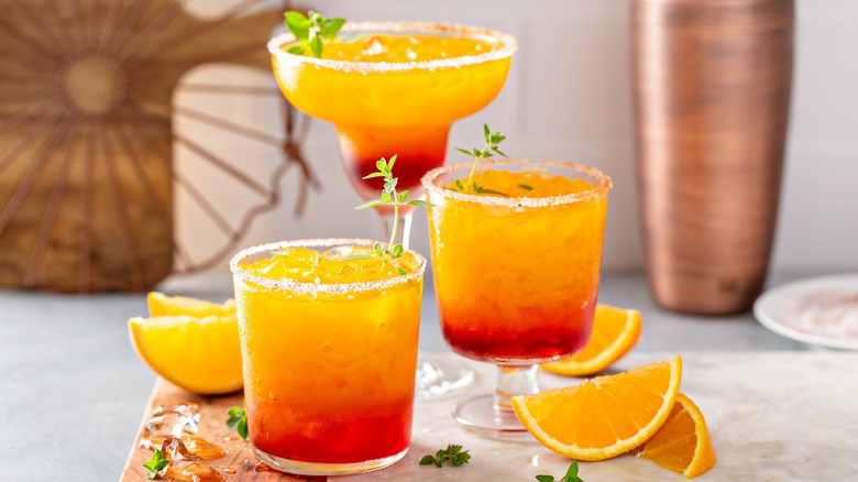 Three prepared tequila sunrise drinks with orange wedges
