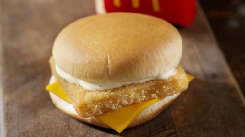 A McDonald's Filet-O-Fish Sandwich sits on a Wood Table with a carton of fries.