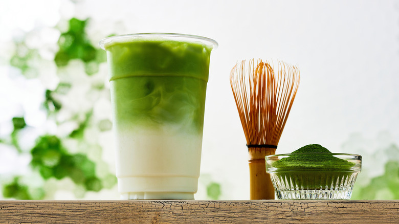 Iced matcha latte beside a ceremonial matcha whisk