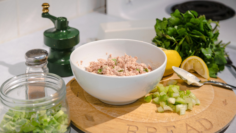 Ingredients needed to make tuna salad, including green onions, dill and parsley, and lemon