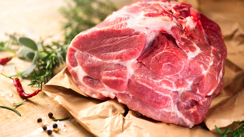 Boston butt or pork shoulder roast on butcher paper, with herbs in background