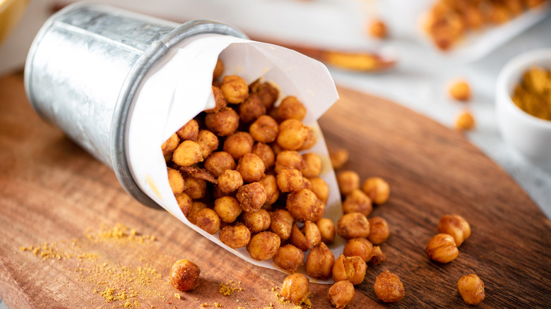 Crispy chickpeas spilling out of a container on a cutting board