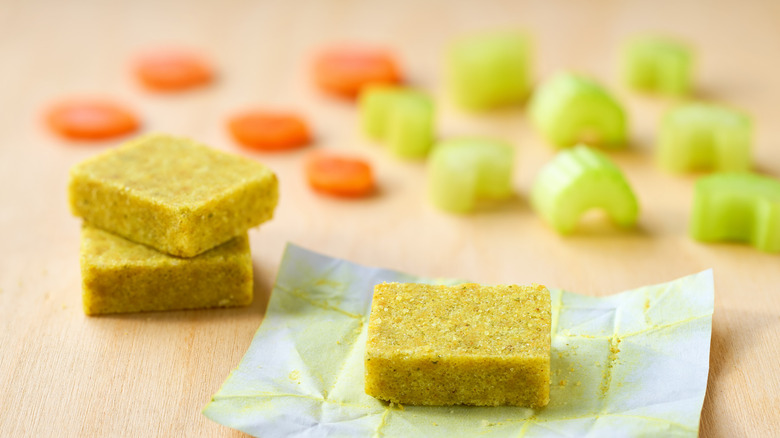 Bouillon cubes with carrot and celery on a wood surface