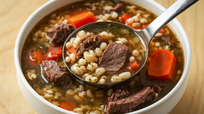 Bowl of beef and barley soup with ladle