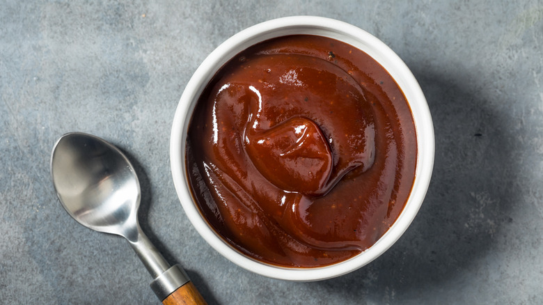 A bowl of barbecue sauce with a spoon beside it