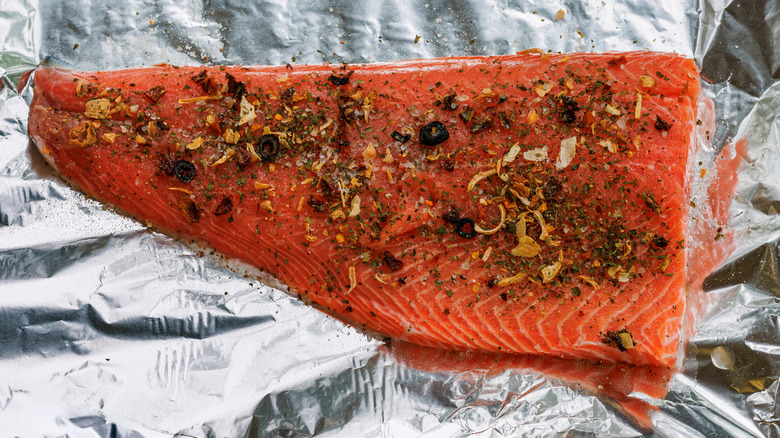 A raw salmon fillet with spices sitting on top of foil
