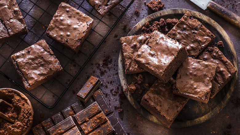 Top view of chocolate brownies displayed on a cooling rack and on a wooden serving tray.