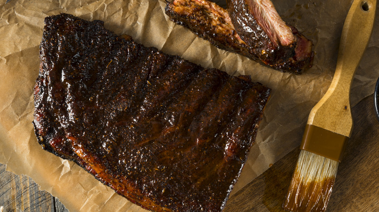 Glazed ribs on butcher paper with a sauce brush nearby.